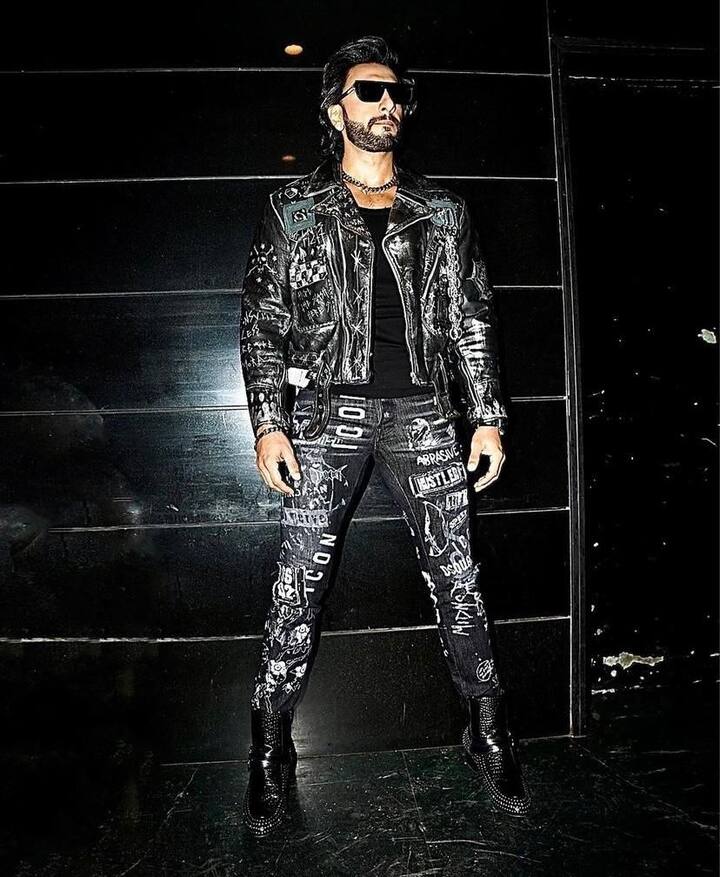 A stylish jacket exuding rockstar vibes: Donning a full black jacket that is well-studded with different fashion accessories, Ranveer exudes sheer bold stylish vibes.
