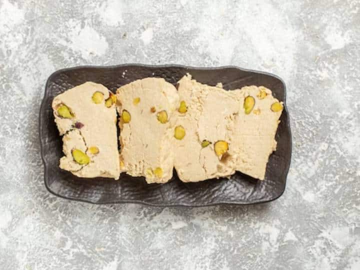 क्या आप मिठाई की दुकानों पर मिलने वाली सामान्य बर्फी से ऊब गए हैं? यह अनोखी और स्वादिष्ट अनानास बर्फी बनाएं जिसे घर पर आसानी से तैयार किया जा सकता है. अपने फल जैसे स्वाद और चिकनी बनावट के साथ, अनानास बर्फी देखने में जितनी सुंदर है, स्वाद में भी उतनी ही अच्छी है. इस स्वादिष्ट बर्फी को बनाने के लिए आपको बस अनानास, नारियल, कस्टर्ड पाउडर, चीनी और घी जैसी कुछ सामग्री की आवश्यकता होगी. अनानास बर्फी की बनावट कुछ-कुछ कराची हलवे जैसी होती है. हमने रेसिपी को सरल रखा है, हालाँकि, आप स्वाद बढ़ाने के लिए अपनी पसंद के कटे हुए मेवे मिला सकते हैं. अनानास बर्फी को हल्का पीला रंग देता है लेकिन अगर आप चाहते हैं कि रंग गहरा हो तो आप इसे बनाते समय इसमें कुछ खाद्य रंग मिला सकते हैं.