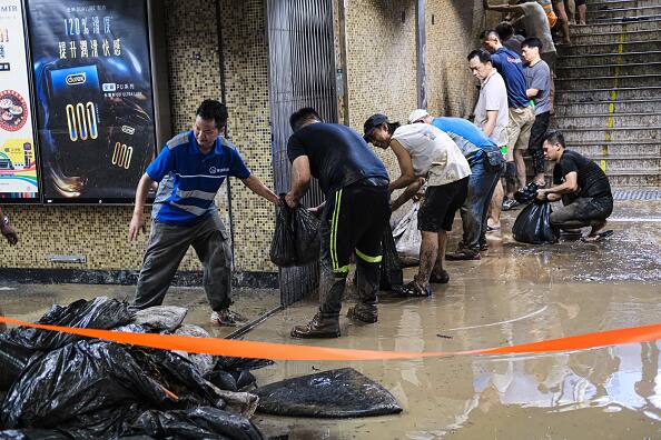 Volunteers carry bags and clean up inside a tube station in Hong Kong, China, following record-breaking rains. (Source: Getty)