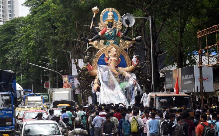 कार्यशाळेतून मूर्ती मंडपामध्ये नेत असताना रस्त्यावर गणेशभक्तांची मोठ्या प्रमाणात गर्दी होते. (Photo : PTI)