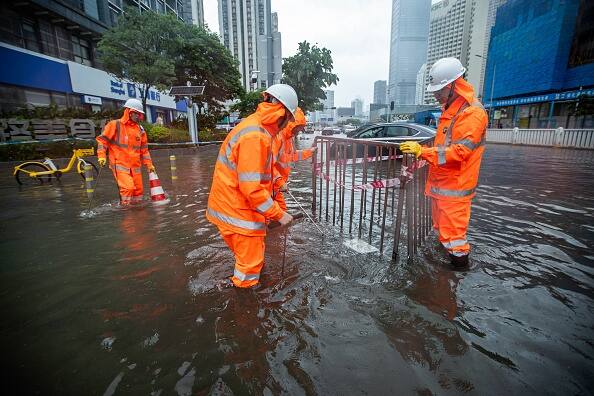 Workers are seen on a flooded street in Shenzhen, Guangdong province, China, following the city's highest rainfall since records began in 1952. (Source: Getty)