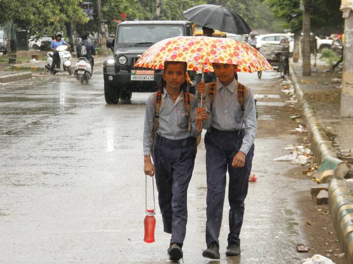 Students on their way to school amid rain in Gurugram on Friday. (Photo: PTI)