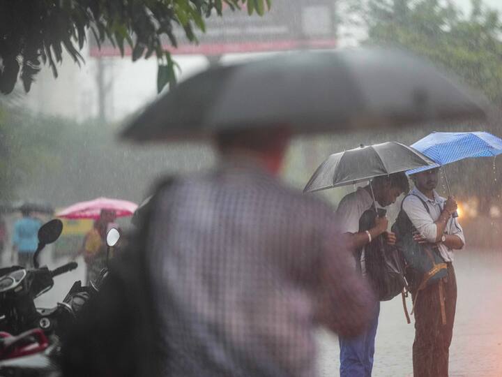 Commuters wait for buses at a stop during rain in UP's Ghaziabad on Friday. (Photo: PTI)