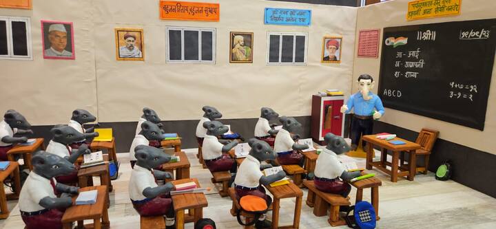 शाडूच्या मातीपासून शिक्षकाच्या वेषातील गणपती बाप्पा, विद्यार्थी रूपातील मूषक, बाकडे, फळा, खडू, पेन्सिल अशा साहित्याचा वापर यात केला आहे.