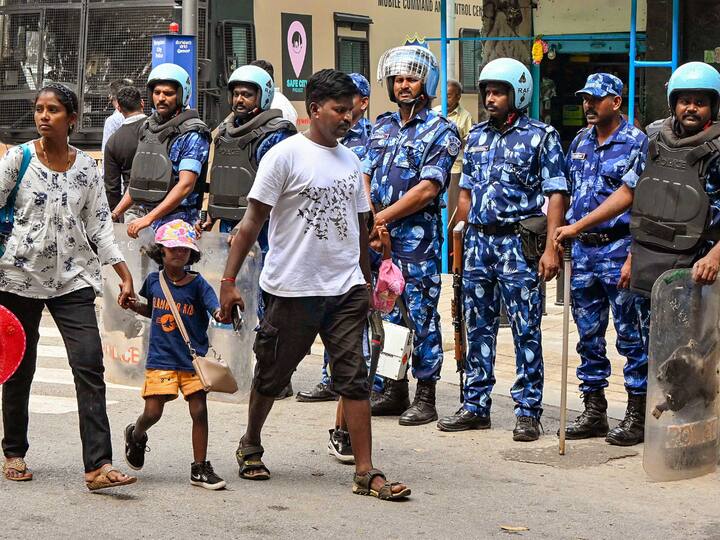 A couple walking with a small child in front of the Rapid Action Force (RAF). The Cauvery River water dispute between the two southern states has been going on for decades. The issue flared up recently after an order from the Cauvery Water Management Authority (CWMA) asking Karnataka to release 5000 cusecs of water to Tamil Nadu for 15 days from September 13. (Image Source: PTI)