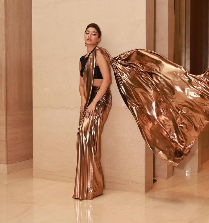 In this bold and edgy black and gold saree ensemble, Saiee showcases her fashion prowess. The metallic gold saree paired with an edgy blouse exudes a sense of contemporary elegance and style. (Image Source: Instagram/ Saiee M Manjrekar)