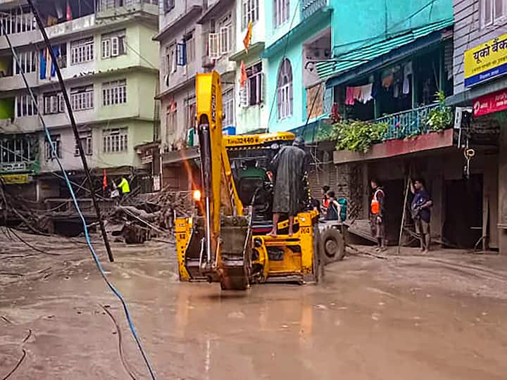 Rescue workers use an excavator to remove debris in a flooded locality in north Sikkim on Wednesday. (Source: PTI)