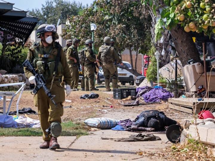 Israeli soldiers stand near the body of a Palestinian militant in Kfar Aza, in the south of Israel, bordering Gaza Strip. (Image Source: Getty)