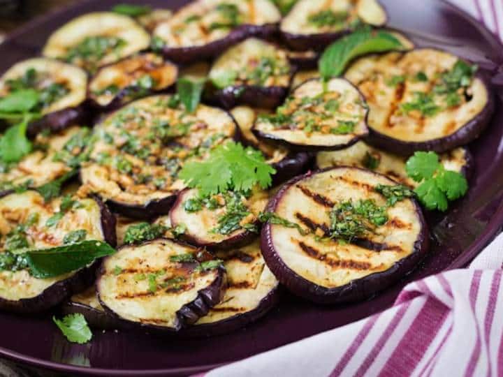 इसके बाद मध्यम आंच पर एक ग्रिल पैन रखें. और पैन में एक चम्मच तेल गर्म करें और जल्दी से गोल बैंगन के स्लाइस को ग्रिल पैन पर फैला दें.