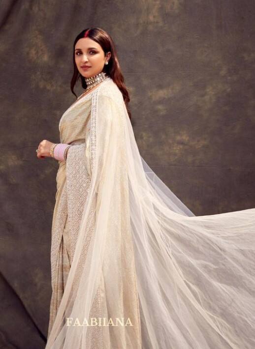 ਪਰਿਣੀਤੀ ਨੇ ਸੰਧੂਰ ਅਤੇ ਉਸਦੇ ਹੱਥਾਂ ਵਿੱਚ ਹਲਕੇ ਗੁਲਾਬੀ ਚੂੜੀਆਂ ਦੇ ਨਾਲ ਇੱਕ ਸਫੈਦ ਚਮਕਦਾਰ ਸਾੜੀ ਪਾਈ ਦਿਖਾਈ ਦਿੱਤੀ। ਉਸਨੇ ਲੇਅਰਡ ਨੇਕਲੈਸ ਅਤੇ ਰਿੰਗਾਂ ਨਾਲ ਆਪਣਾ ਲੁੱਕ ਪੂਰਾ ਕੀਤਾ।