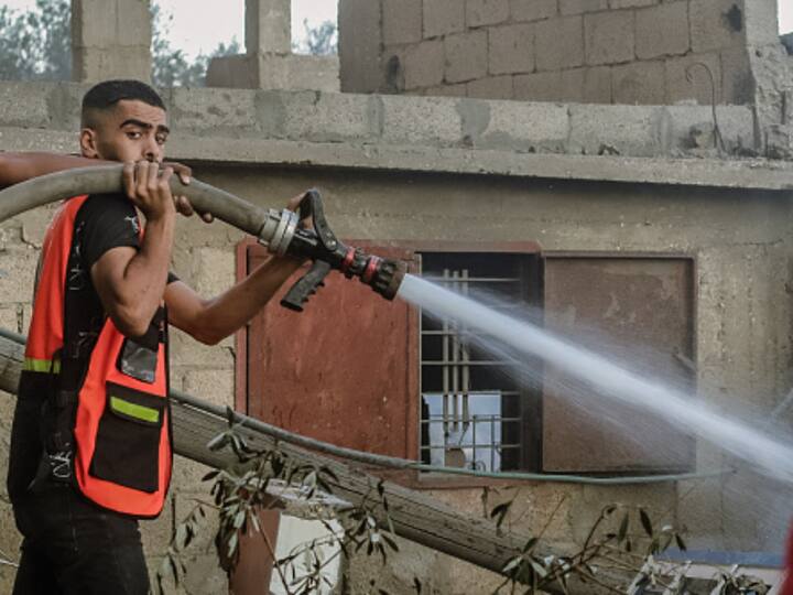 A member of the rescue team extinguishes the fire on the buildings destroyed by Israeli airstrikes. (Photo: Getty)
