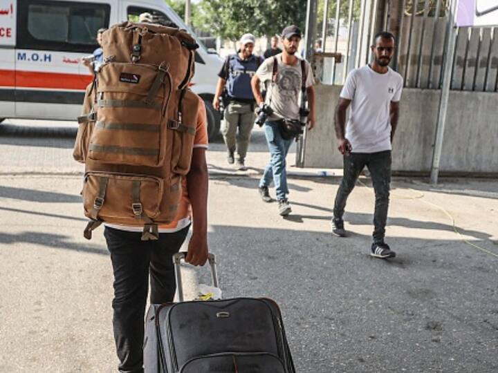 A person walks with their luggage towards the Rafah border crossing on Wednesday after it was opened for the first time. (Source: Getty)