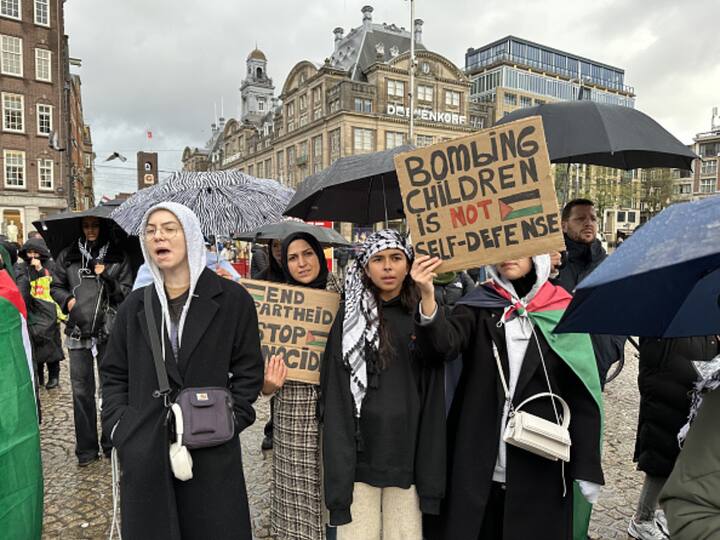 People gather as they carry Palestinian flags and banners to stage a demonstration in support of Palestinians at Dam Square in Amsterdam, Netherlands on Sunday. Image Source: Getty Images