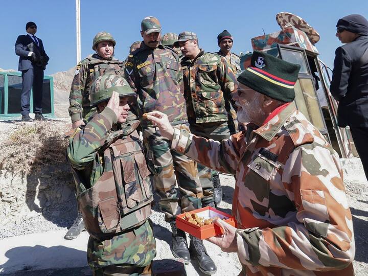 A soldier salutes PM Modi before being offered a sweet by the Prime Minister in Lepcha, Himachal Pradesh. (Source: PTI)