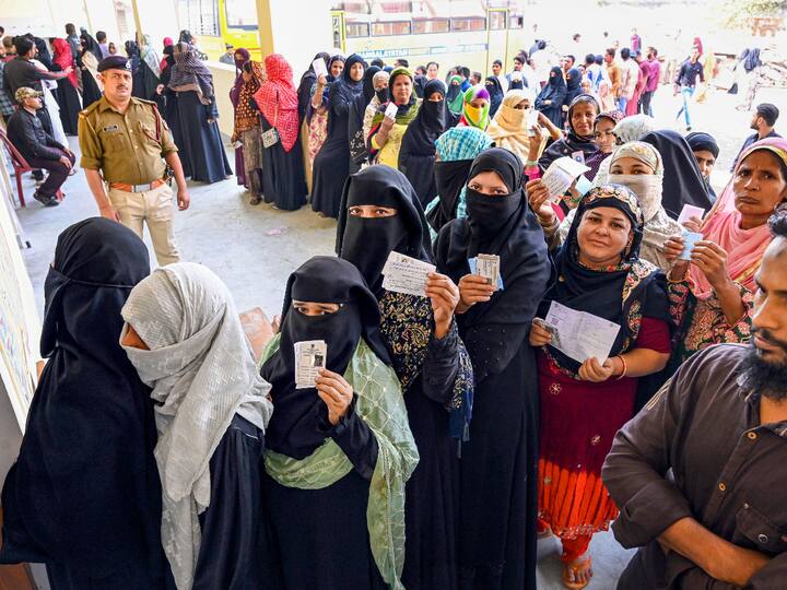 Women in burqas show their Voters’ ID cards as they wait to cast their vote in Jabalpur, MP. (Source: PTI)