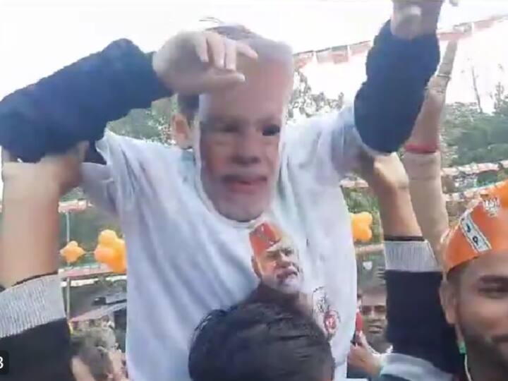 A child wearing a PM Narendra Modi t-shirt and mask dances on the shoulders of a man after the party showcased a big lead in Rajasthan. (Source: ANI)