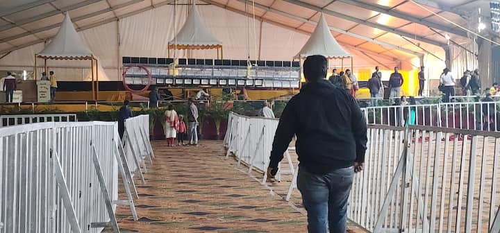 Dhirendra Krishna Shastri News: पूर्वी दिल्ली के शाहदरा इलाके में एक बार फिर से बागेश्वर धाम के पीठेश्वर पंडित धीरेंद्र कृष्ण शास्त्री हनुमंत राम कथा के श्रवण के साथ उनके श्रद्धालुओं का बहुप्रतीक्षित दिव्य-दरबार में शामिल होने का लाभ देने जा रहे हैं. इस बार यह आयोजन सीबीडी ग्राउंड में किया जा रहा है, जिसके लिए तमाम तरह की तैयारियां 24 घंटे कर्मचारियों की बड़ी टीम करने में जुटी हुई हैं. आज यानी 15 दिसंबर की शाम से ही दिल्ली NCR समेत अलग अलग राज्यों से आ रहे श्रद्धालु पंडाल में अपनी जगह लेने सुरु कर चुके हैं. बस अब बाबा के आने का इंतजार है.