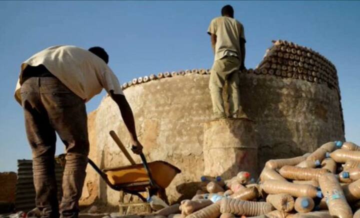 নাইজিরিয়ার মতো দেশে এই মুহূর্তে প্লাস্টিকের বোতল দিয়ে তৈরি এমন বাড়ি গজিয়ে উঠছে সর্বত্র। সাধারণত বাড়ি চৌকো হয়। কিন্তু প্লাস্টিকের বোতলে বালি ভরে যে বাড়ি তৈরি হচ্ছে, সেগুলে বৃত্তাকার। এক একটি বাড়ি তৈরি করতে ১৪ হাজার প্লাস্টিকের বোতলের প্রয়োজন পড়ে। তাতেও ইঁট-সিমেন্ট দিয়ে তৈরি বাড়ির চেয়ে এই বাড়ি তৈরির খরচ ৬৭ শতাংশ কম। এক একটি বাড়ি কমপক্ষে ৩০০ বছর টিকে থাকতে পারে।    ছবি: টাটেহ্ লেহবিব বারিকার ট্যুইটার হ্যান্ডল থেকে সংগৃহীত।