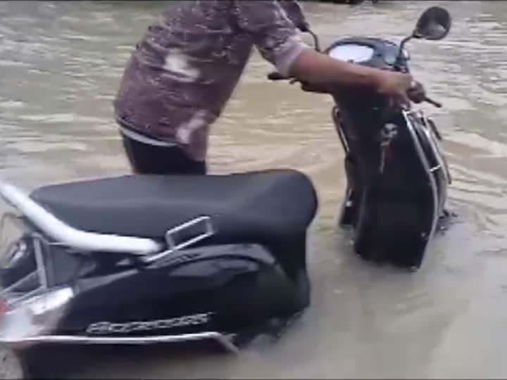 A man drags his two-wheeler through a heavily flooded road in Thoothukudi, Tamil Nadu on Tuesday morning. The Chennai Meteorological Department has reported the likelihood of moderate thunderstorms, lightning, and rainfall in isolated areas across several districts of Tamil Nadu and Karaikal.  (Source: ANI)