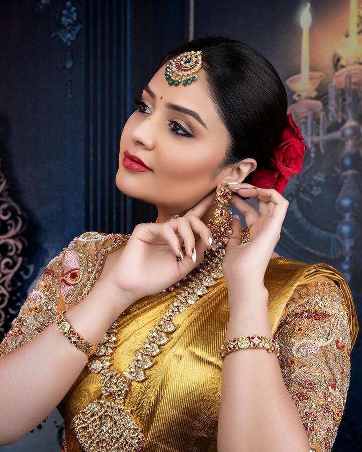 బంగారు ఆభరణాలతో ముస్తాబై.. గోల్డెన్ చీరకు తగ్గ డిజైనర్​ బ్లౌజ్​లో అందంగా ముస్తాబైంది ఈ భామ. తల్లో ఎర్ర గులాబీలు పెట్టుకుని.. వింటేజ్ వైబ్స్ ఇస్తుంది.