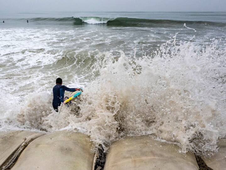 A surfer jumps into the water as a wave crashes onshore. Breaking waves of 26-30 feet are likely to crash at west-facing beaches along the central and northern California coastline. (Image Source: Getty)