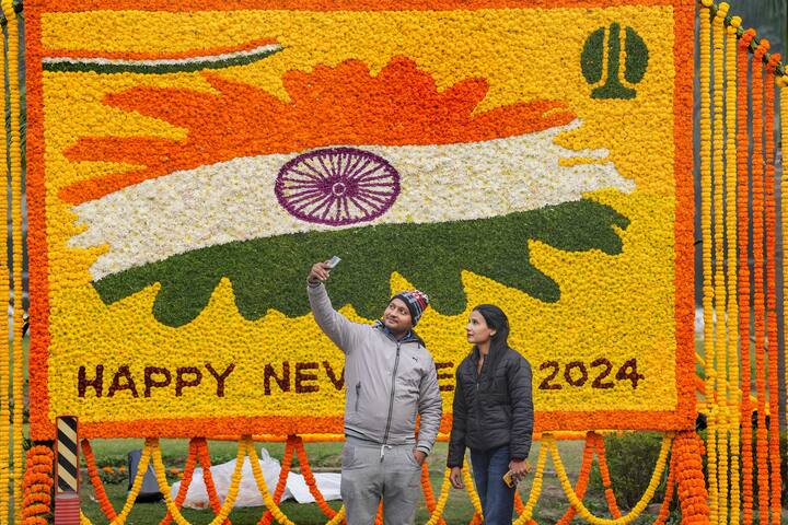 People take selfie in the backdrop of a floral decoration of the Happy New Year 2024, in New Delhi. (Image Source: PTI)