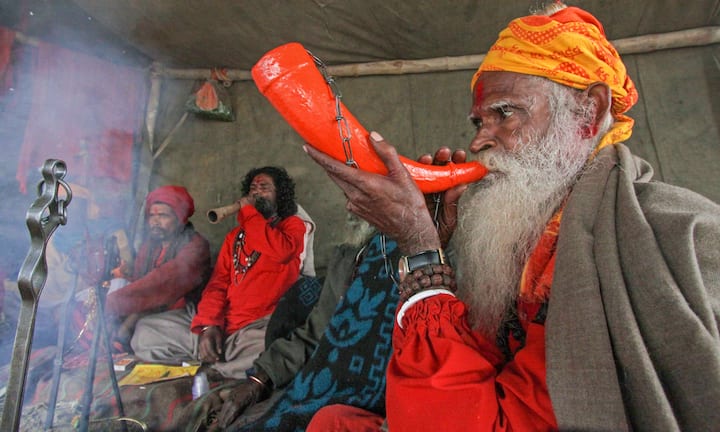 A sadhu blows a horn instrument to attract devotees gathered on Makar Sankranti festival to take holy dip in the Ajoy river, in Birbhum district of West Bengal. (Image Source: PTI)