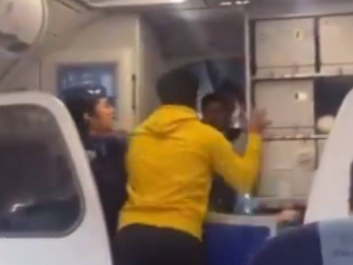 इंडिगो की फ्लाइट्स लेट होने के चलते सोशल मीडिया पर यात्रियों का गुस्सा खूब फूट रहा है. इसी बीच एक वीडियो वायरल हो रहा है, जिसमें कैप्टन फ्लाइट के Delay होने की बात करता है तो पीछे बैठा एक यात्री आगे आकर कैप्टन को पंच मार देता है.