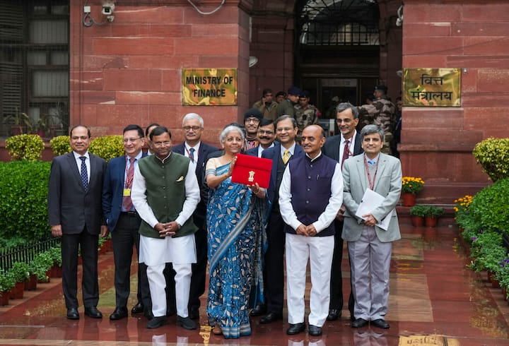 2024 ஆம் ஆண்டின் இடைக்கால பட்ஜெட் தாக்கலில், மத்திய நிதியமைச்சர் நிர்மலா சீதாராமன், ப்ளூ- கிரீம் நிற டஸ்ஸார் புடவையை அணிந்துள்ளார். இது மஹாராஷ்டிராவை சார்ந்தது. (Photo Credits : PTI)