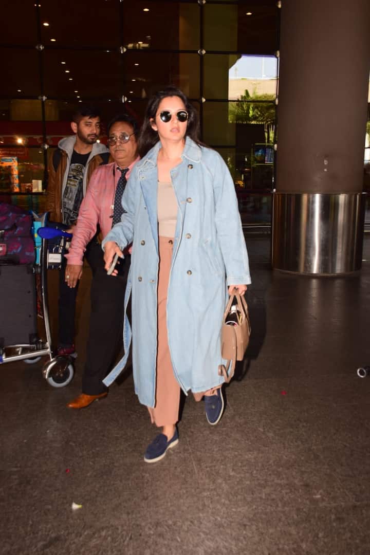 Sania was seen at the airport in brown pants, beige top with blue trench coat.