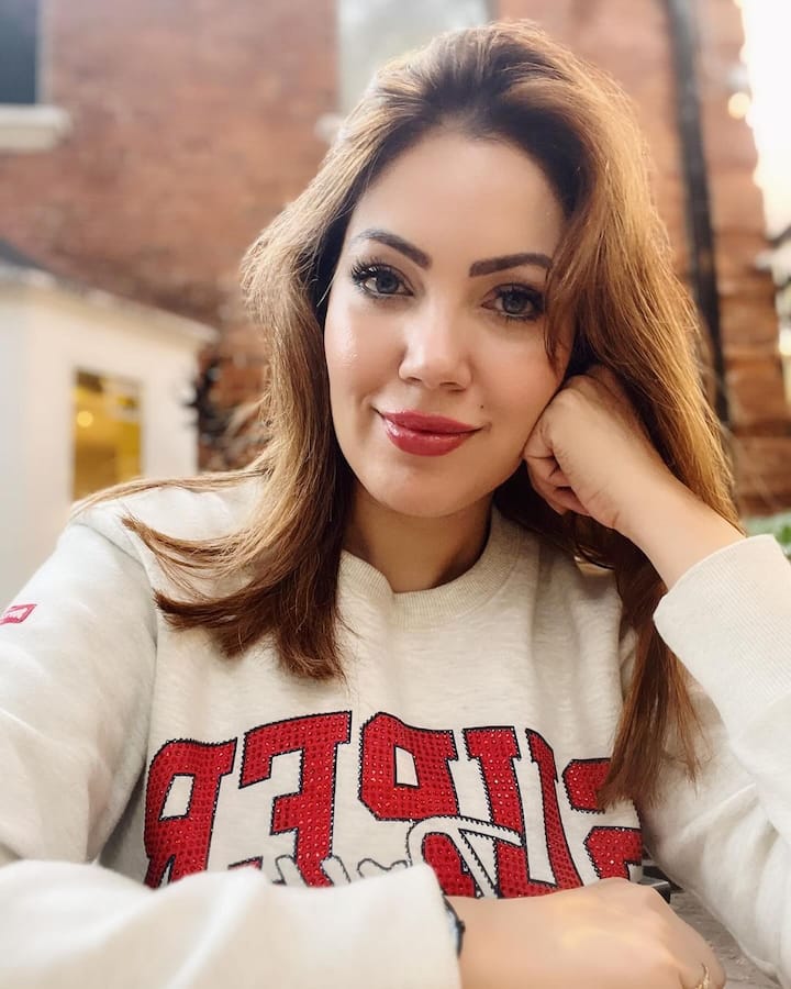 In another selfie, she is wearing a white sweater, with red glossy lips and blushed up look.