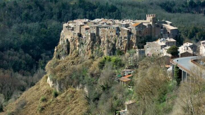 Calcata-র উপর গড়ে ওঠা বাড়িগুলি মূলত পাথর কেটে তৈরি। রাস্তার পাশে সারি দিয়ে ছোট ছোট দোকান রয়েছে। সেখানেই চেয়ার নিয়ে পথচলতি মানুষজনের ছবি তোলেন শিল্পীরা। চা-কফি-পানীয়ের দোকানও রয়েছে। ছবি: ফ্রিপিক।