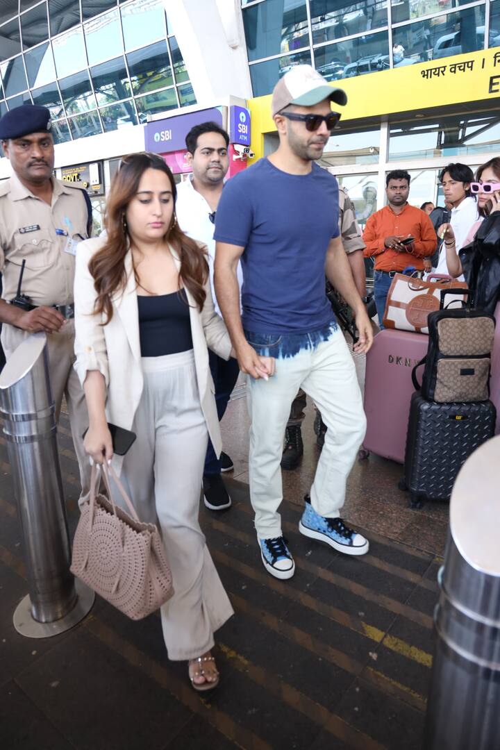 The Bollywood actor held his wife close as they made their way through the crowded airport on a busy Monday.