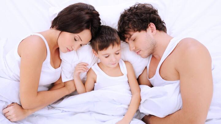 बच्चों के साथ सोना, जिसे हम 'को-स्लीपिंग' भी कहते हैं, बहुत से परिवारों में एक आम बात है. यह नवजात शिशुओं के साथ शुरू होता है और कई बार बच्चे की उम्र बढ़ने के साथ भी जारी रहता है. लेकिन, एक उम्र के बाद इसे बंद कर देना चाहिए. आइए जानते हैं कि यह उम्र क्या है और क्यों इसे बंद करना महत्वपूर्ण है.