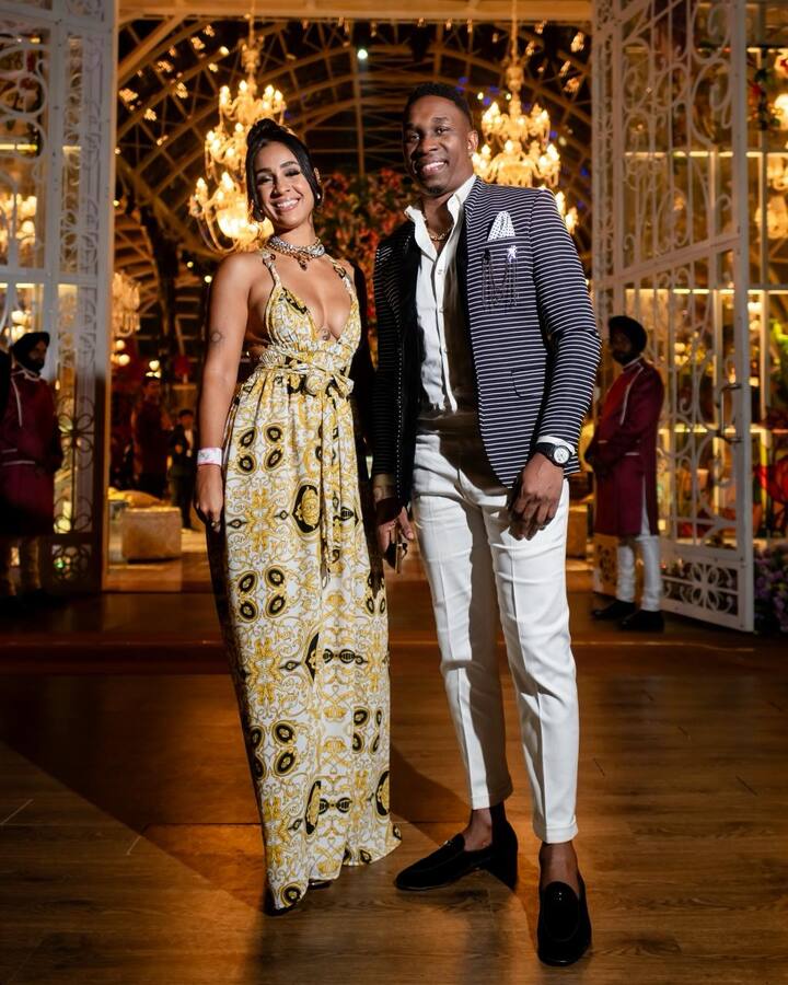 Dwyane Bravo and his glamorous wife make a stylish statement at the grand pre-wedding event in Jamnagar. Bravo sports a stunning striped blazer, while his wife dazzles in a printed gown. (Image source: Manav Manglani)
