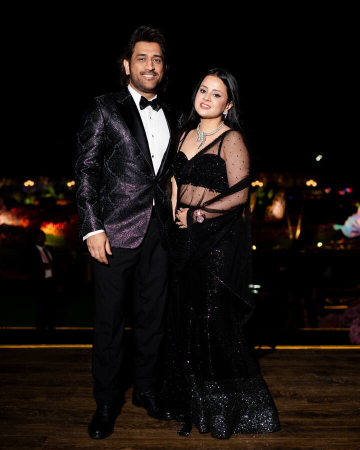 Mahendra Singh Dhoni and Sakshi are twinning in black at Anant Ambani and Radhika Merchant's pre-wedding celebrations in Jamnagar. Dhoni exudes dapper charm in a shimmering black blazer, while Sakshi stuns in a black net saree adorned with diamonds. (Image source: Manav Manglani)