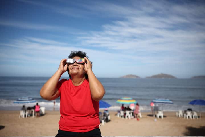 A woman puts on her glasses to see the eclipse on April 08, 2024 in Mazatlan, Mexico. Millions of people have flocked to areas across North America that are in the 