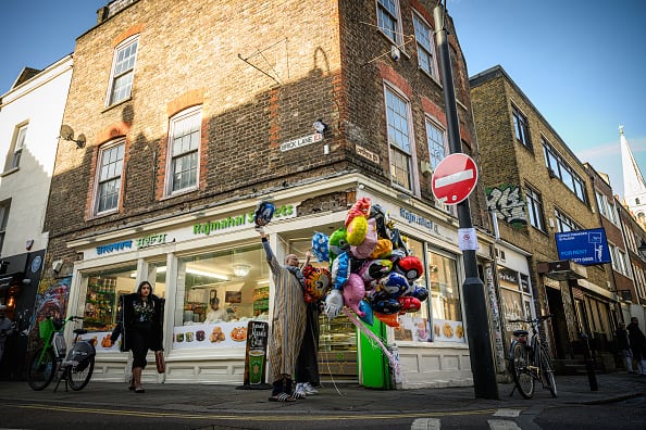 A man sells colourful balloons outside a shop on Brick Lane as Ramadan comes to an end and Muslims around the world begin to celebrate Eid al-Fitr, in London, United Kingdom. (Image Source: Getty)