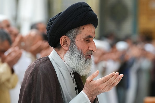 A Shiite Muslim cleric performs morning prayers on the first day of Eid al-Fitr, which marks the end of the holy fasting month of Ramadan, at the Imam Ali shrine in Iraq's shrine city of Najaf. (Image Source: Getty)