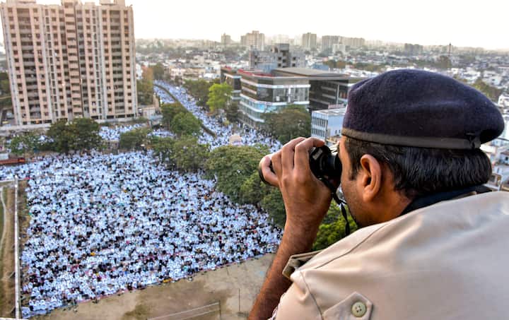A policeman keeps vigil as Muslim devotees offer 'namaz' during Eid-al-Fitr celebrations at Rander Eidgah in Surat. (Image Source: PTI)