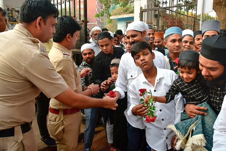 Policemen greet Muslim devotees with roses on the occasion of Eid-al-Fitr, at YMCA ground, in Mumbai. (Image Source: PTI)
