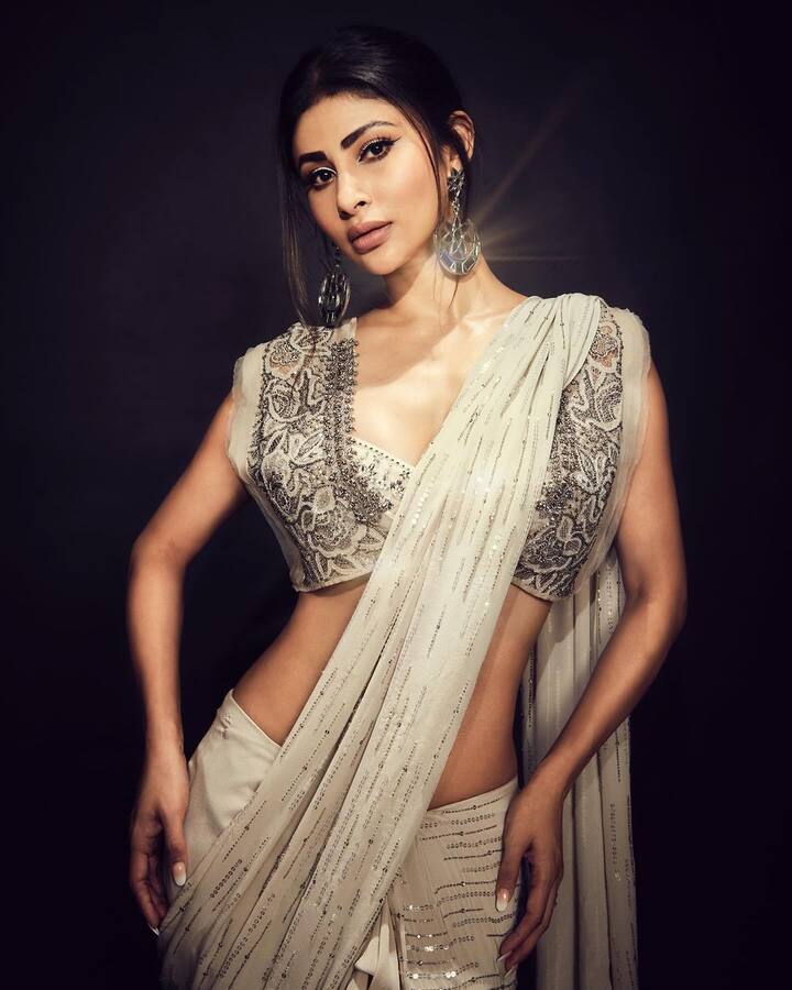 క్రీమ్ కలర్, యాష్​ కలర్ మిక్స్​ ఉన్న శారీలో చాలా అందంగా కనిపించింది. చీరను అందంగా కట్టుకుని.. స్లీవ్ లెస్ డిజైనర్ బ్లౌజ్ ధరించింది.(Images Source : Instagram/MouniRoy)