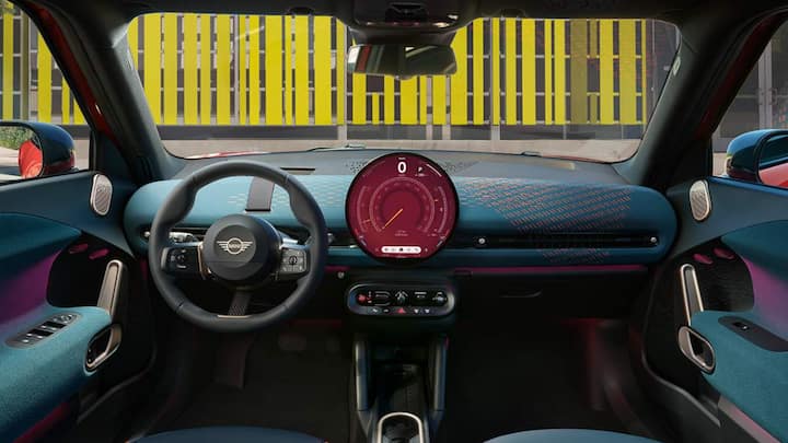 मिनी एसमैन ईवी में लार्ज सेंट्रल OLED डिस्प्ले का इंफोटेनमेंट सिस्टम लगा है. इस कार का कर्व्ड डैशबोर्ड knitted टेक्सटाइल सरफेस का बना हुआ है.