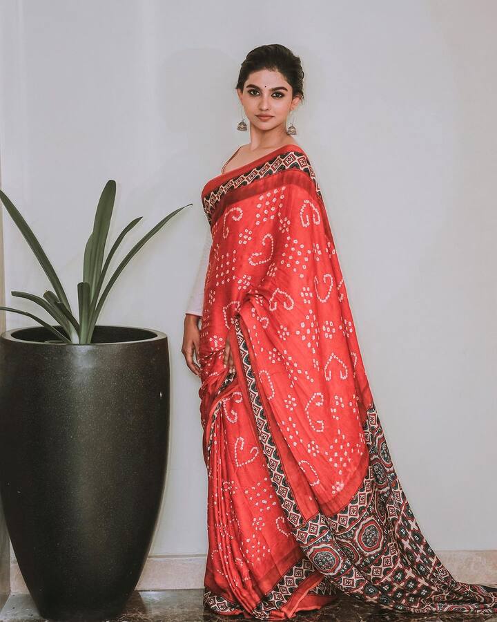 తలను ముడి వేసి.. రెడ్, కషాయం, బ్లాక్ కాంబినేషన్​లో వచ్చిన చీర కట్టుకుని.. వైట్ కలర్ డిజైనర్ బ్లౌజ్​లో అందంగా ముస్తాబైంది. (Images Source : Instagram/Mamitha Baiju)