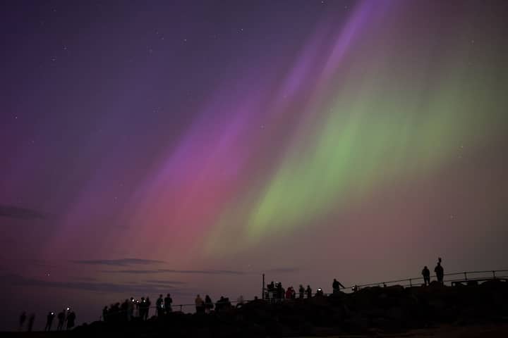 This celestial extravaganza is attributed to a potent solar storm, which, if predictions hold, could persist into Sunday. In this photo, people visit St Mary's lighthouse in Whitley Bay to see the aurora borealis in Whitley Bay, England. (Source: Getty Images)
