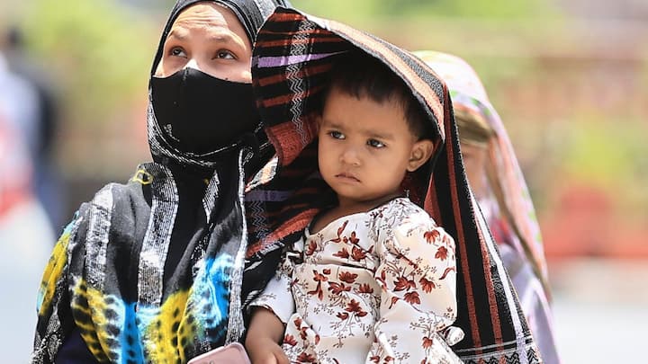 जयपुर में बढ़ती गर्मी से बचने के लिए अपने बच्चे को ढकती एक महिला। (छवि स्रोत: पीटीआई)
