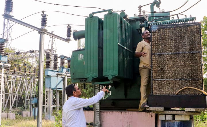 महाराष्ट्र राज्य विद्युत वितरण कंपनी लिमिटेड (एमएसईडीसीएल) के कर्मचारी बुधवार, 29 मई, 2024 को नागपुर में चल रही भीषण गर्मी के बीच ट्रांसफार्मरों की सुरक्षा के लिए वाटर कूलर लगाते हुए। (स्रोत: पीटीआई)