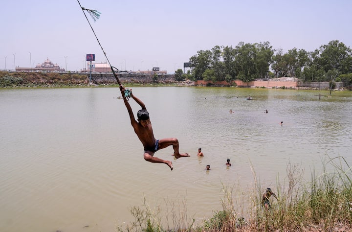 बुधवार, 29 मई, 2024 को नई दिल्ली के कुछ हिस्सों में तापमान 50 डिग्री सेल्सियस तक पहुंचने के कारण लड़के पानी के तालाब में खुद को ठंडा करते हैं। (स्रोत: पीटीआई)