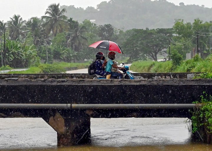 मंगलवार, 28 मई, 2024 को तिरुवनंतपुरम में मानसून से पहले, बारिश से बचने के लिए दोपहिया वाहन चलाते समय यात्री छाते का उपयोग करते हैं। (स्रोत: पीटीआई)