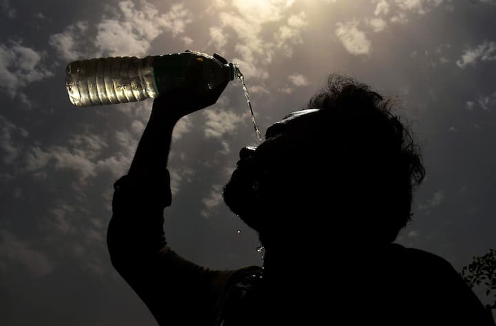 गुरुग्राम में बुधवार, 29 मई, 2024 को भीषण गर्मी के बीच एक व्यक्ति अपने चेहरे पर पानी छिड़कता हुआ। (स्रोत: पीटीआई)